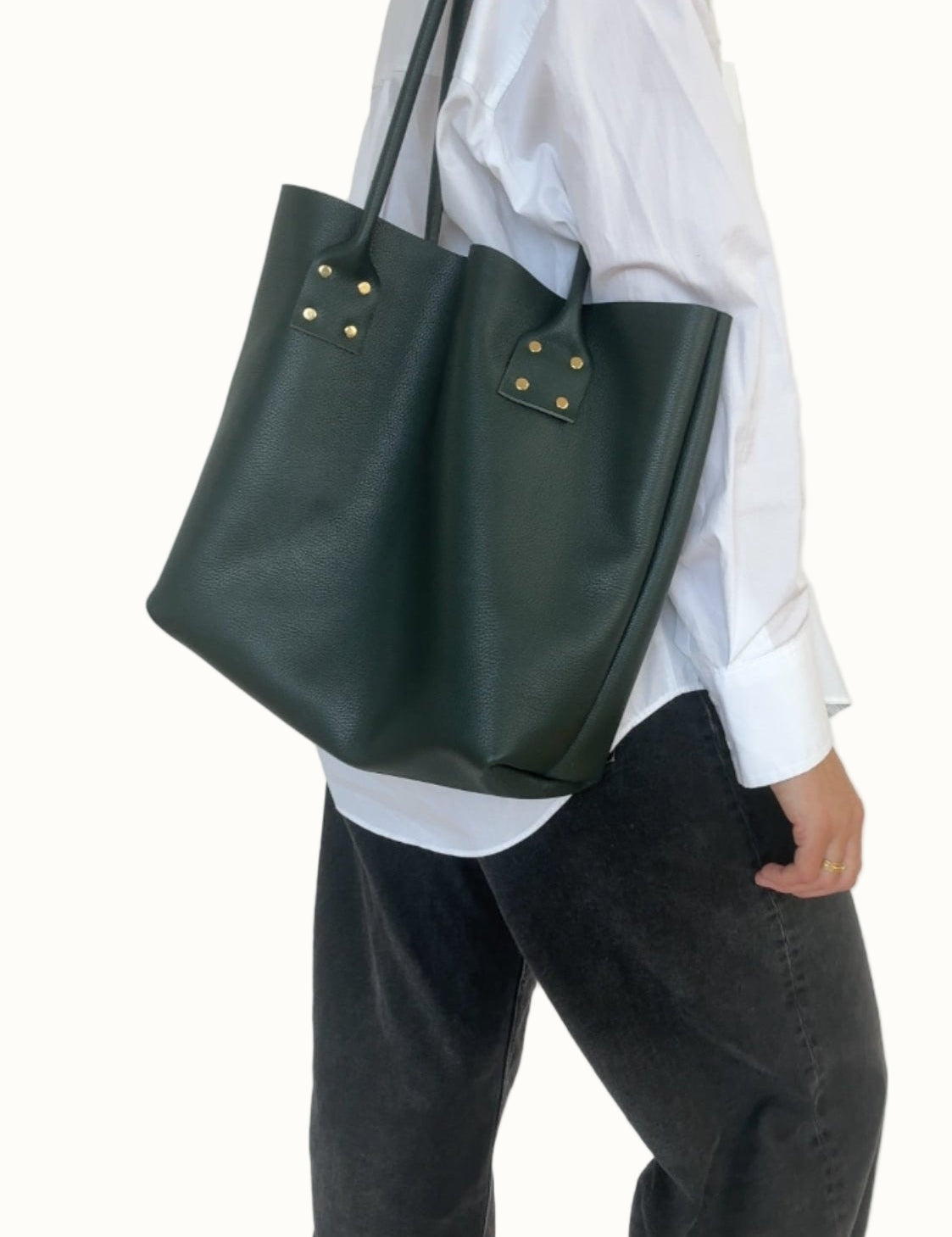 Person wearing a white shirt and dark green tote bag on a plain background