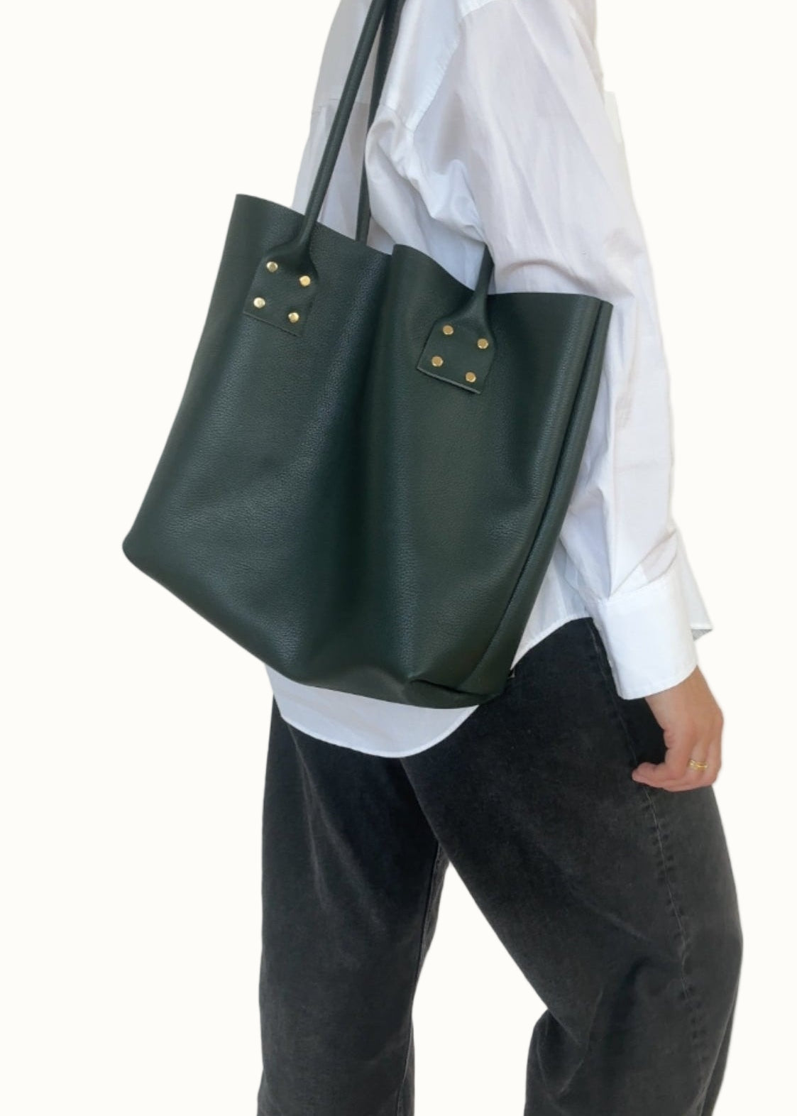 Person wearing a white shirt and dark green tote bag on a plain background