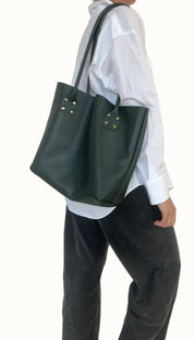 Person wearing a white shirt and dark green tote bag on a plain background