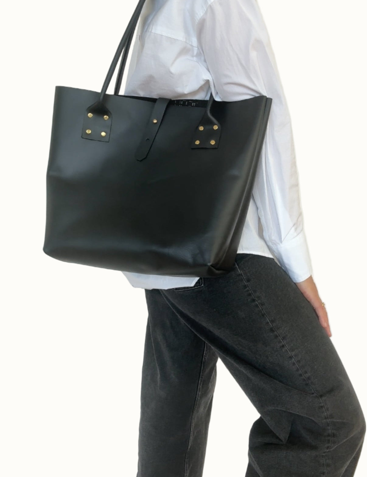 Person wearing a black tote bag against a plain background