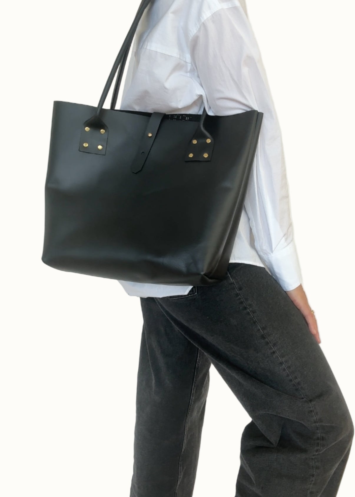 Person wearing a black tote bag against a plain background