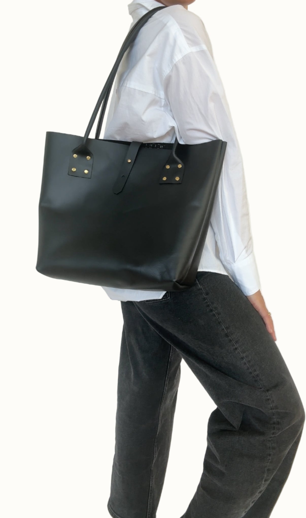 Person wearing a black tote bag against a plain background