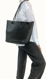 Person wearing a black tote bag against a plain background
