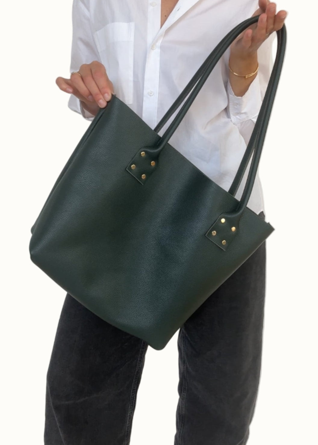 Person holding a green handbag against a white background