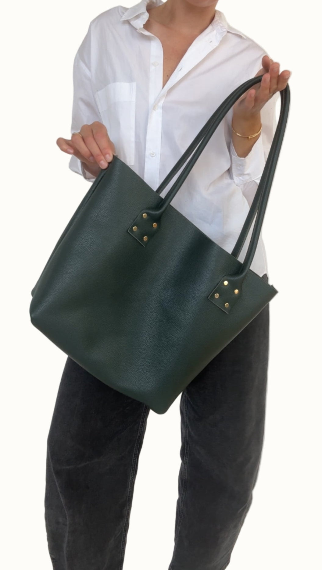 Person holding a green handbag against a white background