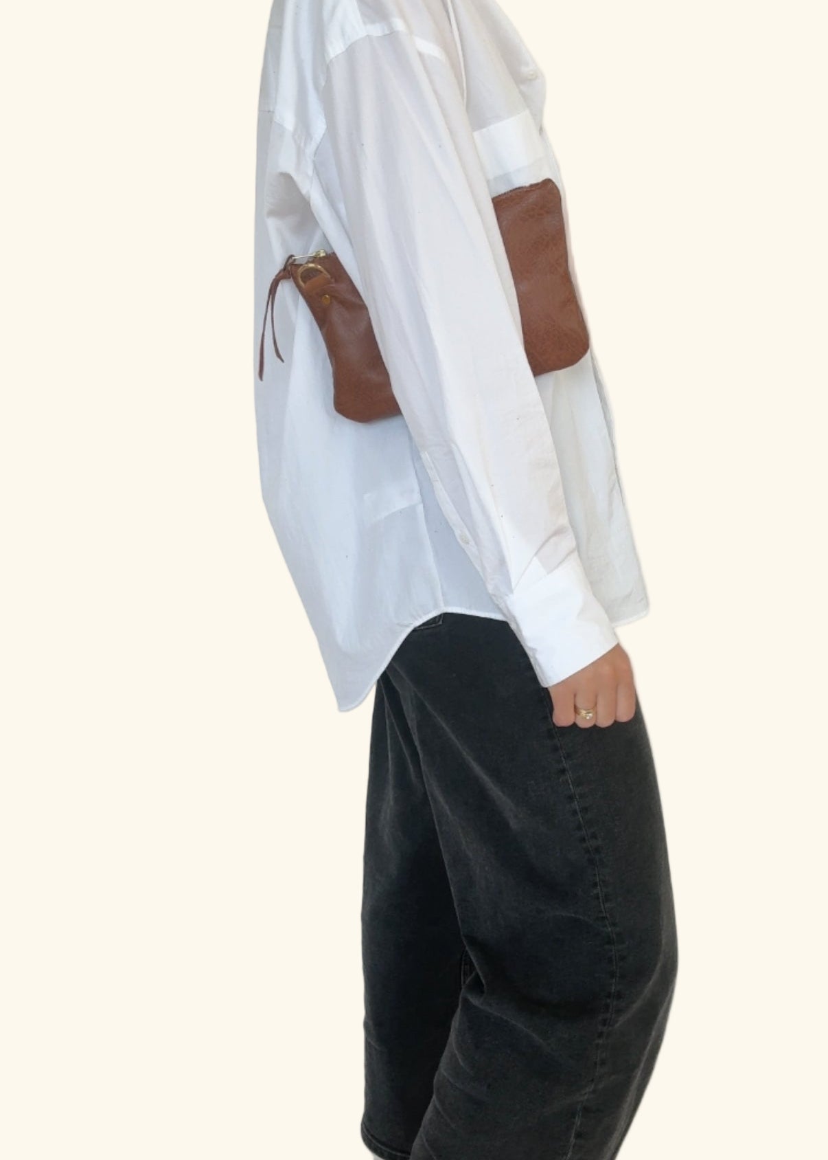 Person wearing a white shirt with brown accents and black pants on a white background