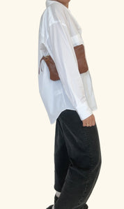 Person wearing a white shirt with brown accents and black pants on a white background
