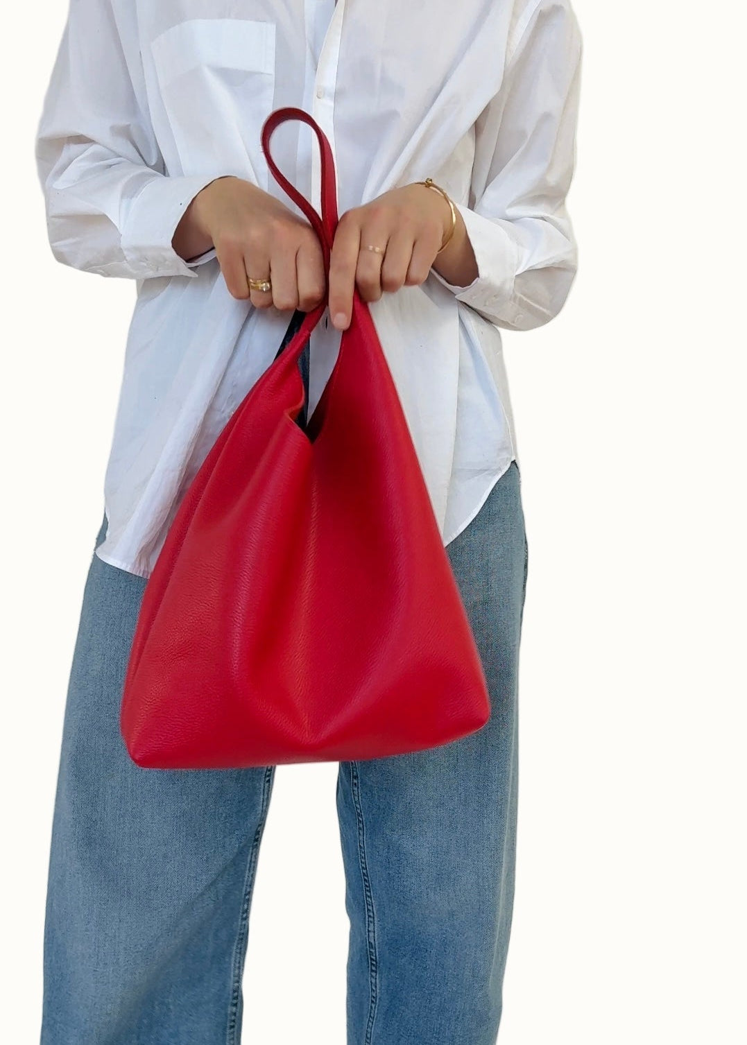 Person holding a red bag with a white shirt and blue jeans on a white background