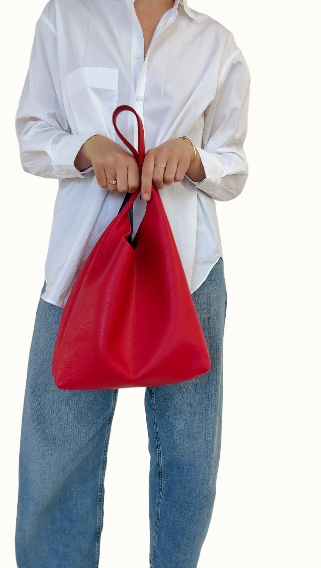 Person holding a red bag with a white shirt and blue jeans on a white background