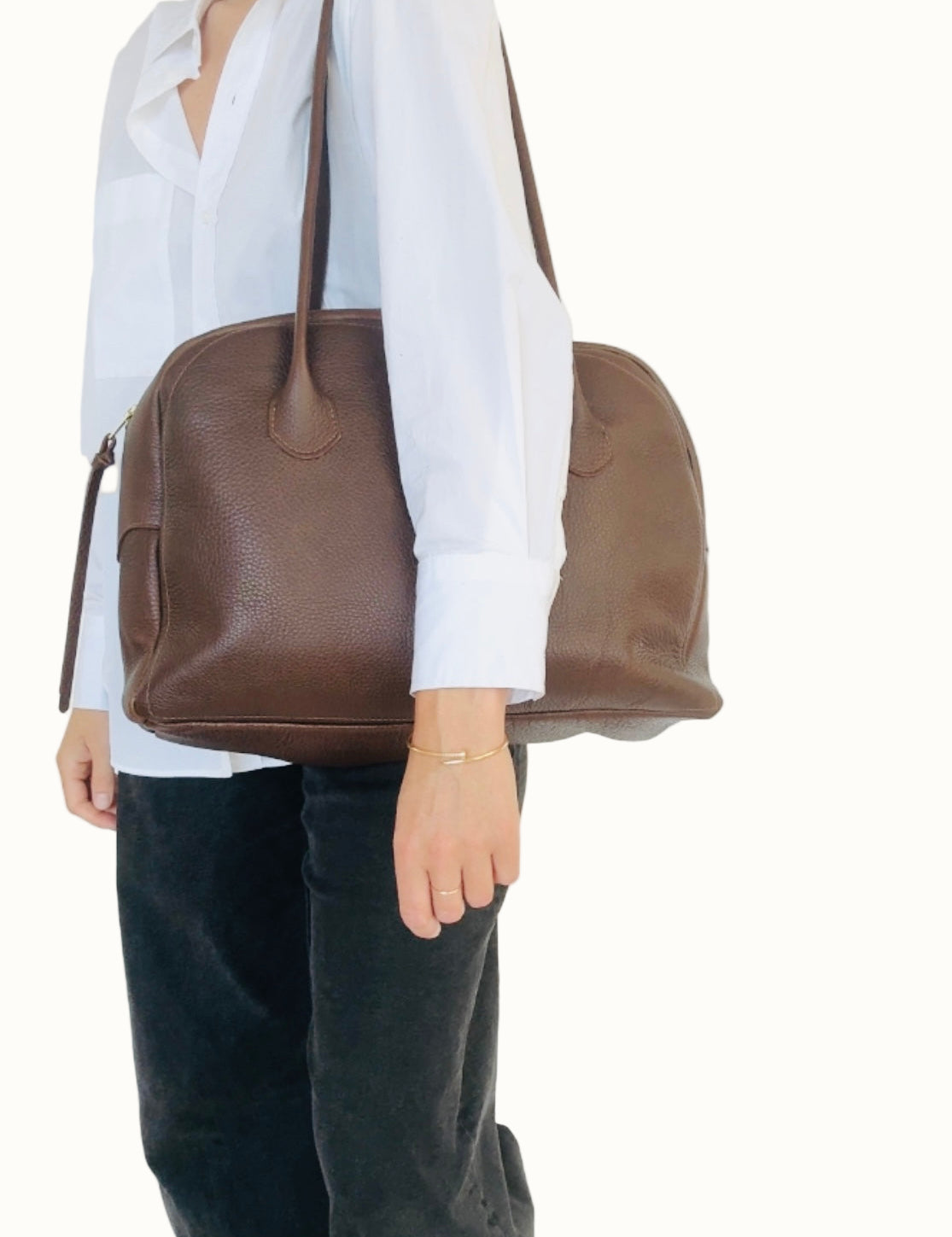 Person holding a brown leather bag against a white background