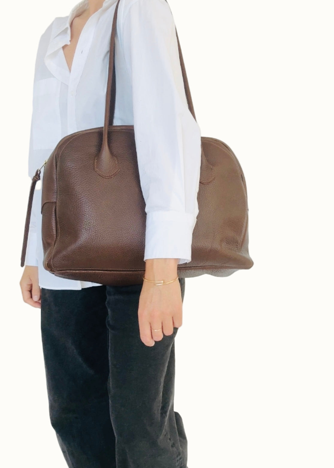 Person holding a brown leather bag against a white background