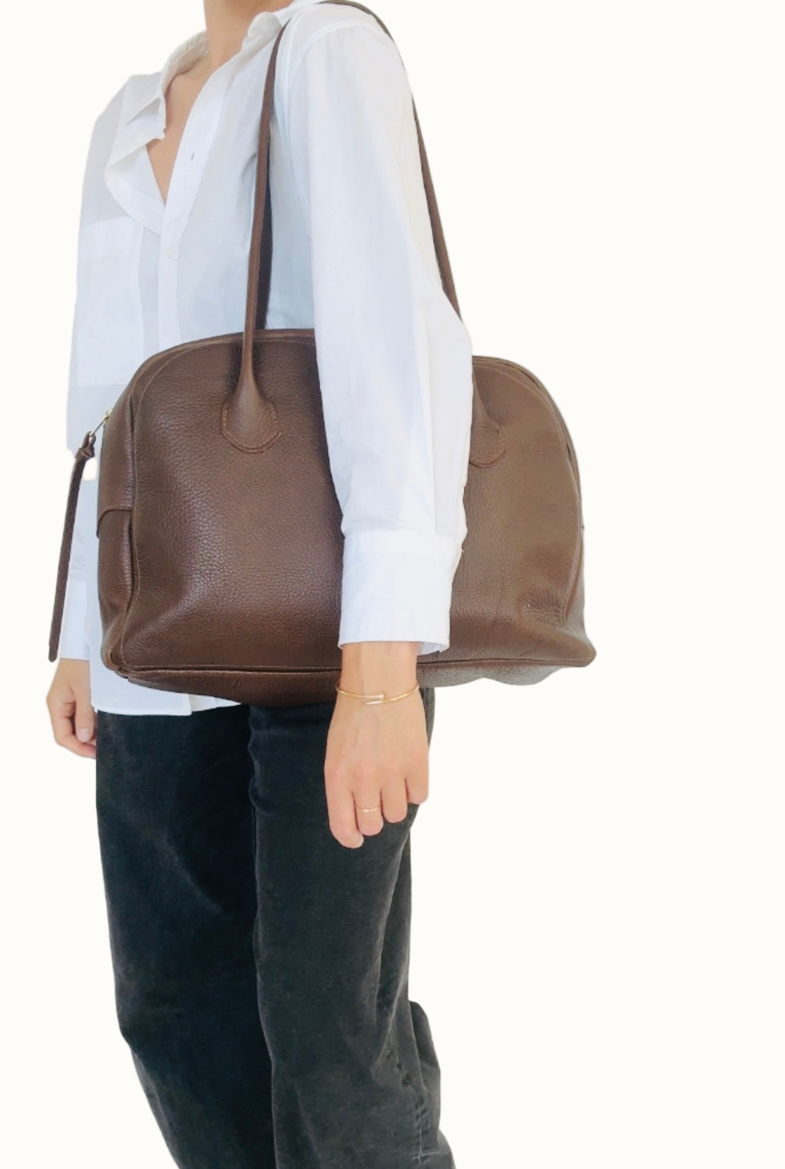 Person holding a brown leather bag against a white background