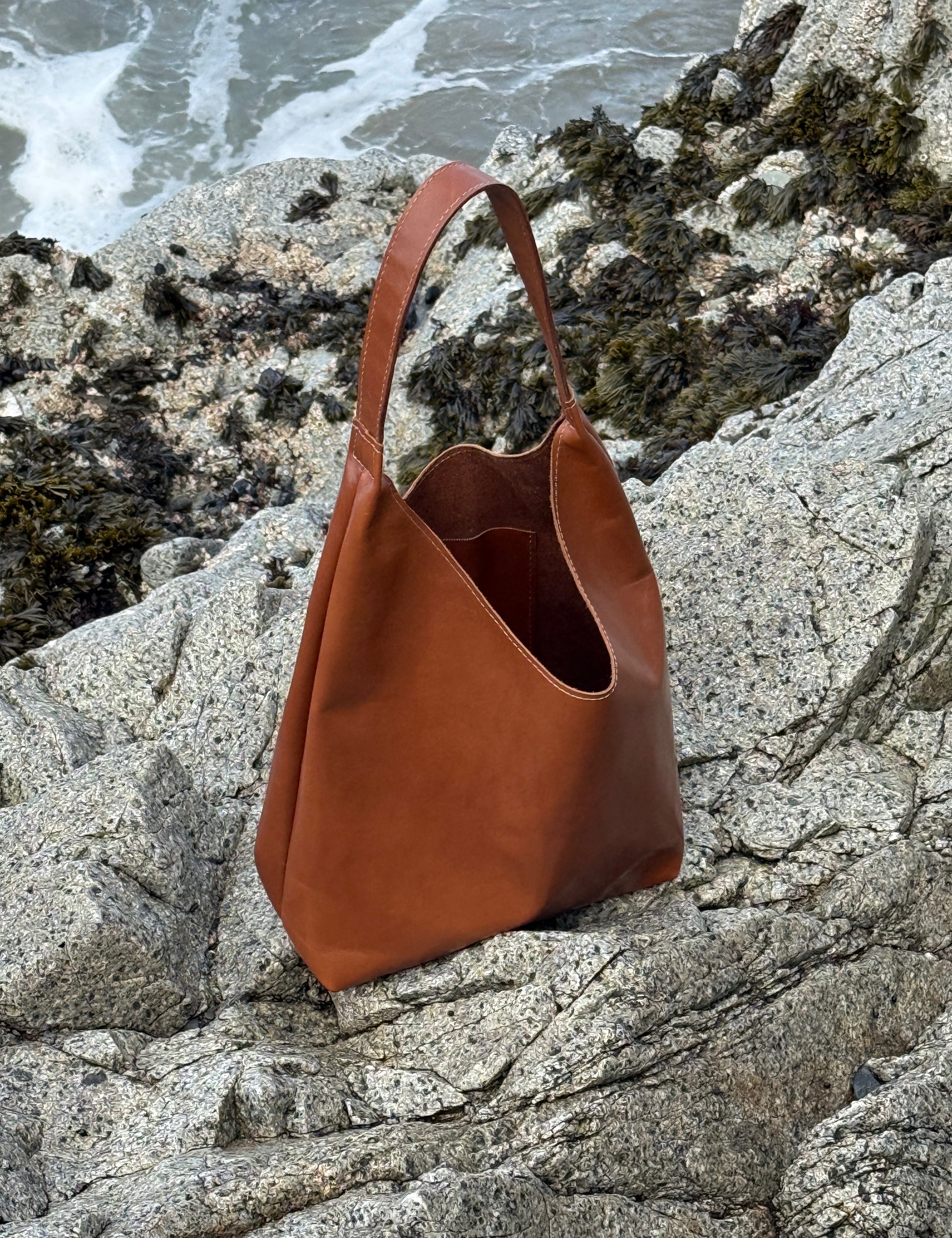 Brown leather bag on a rocky surface near water