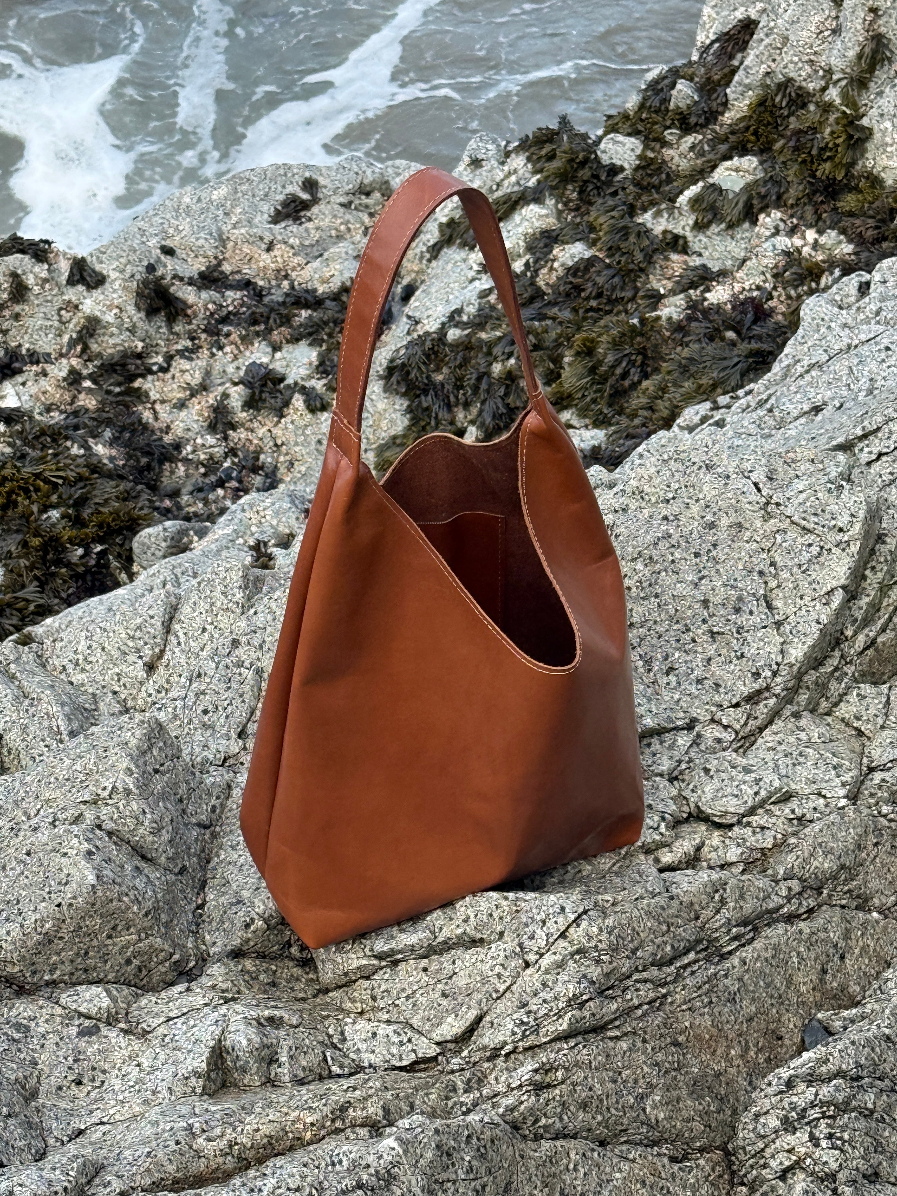 Brown leather bag on a rocky surface near water