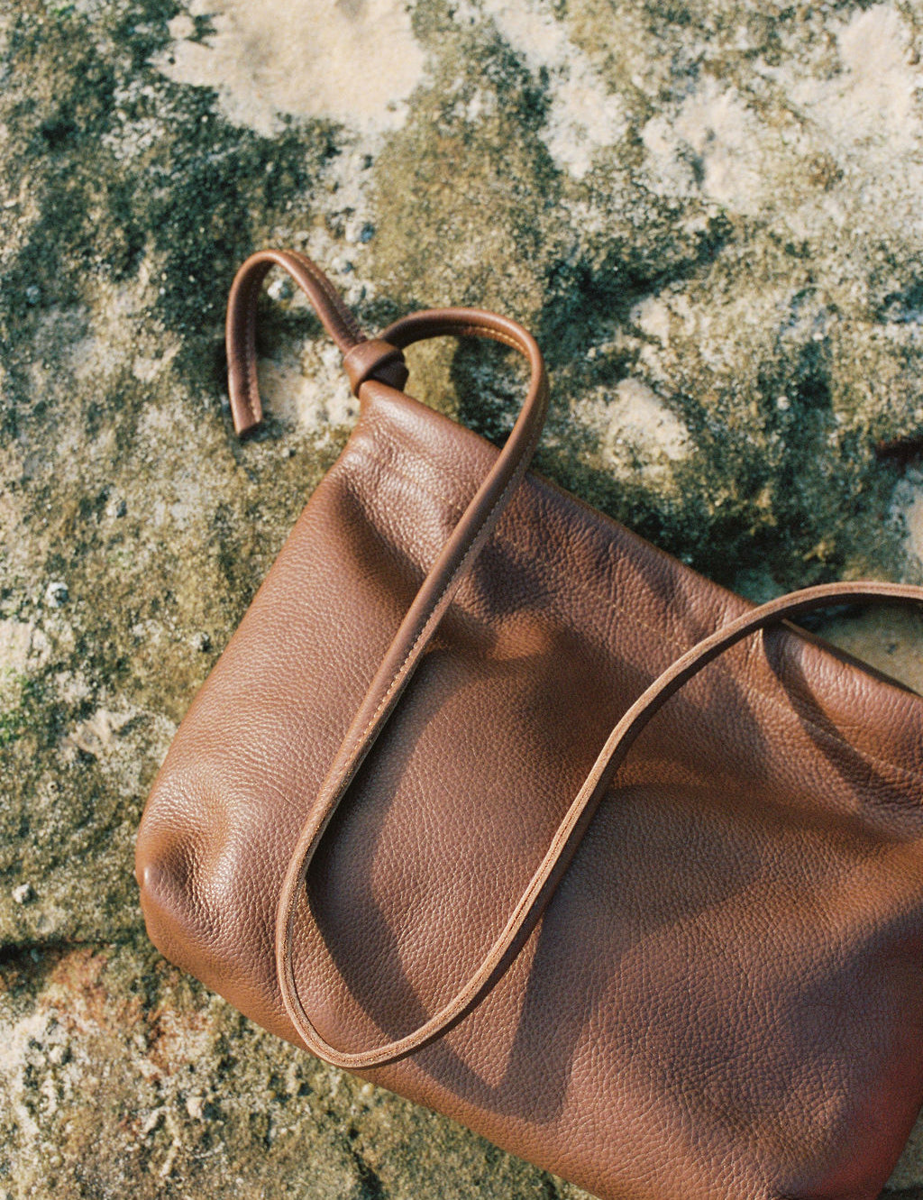 Brown leather handbag on a textured stone surface