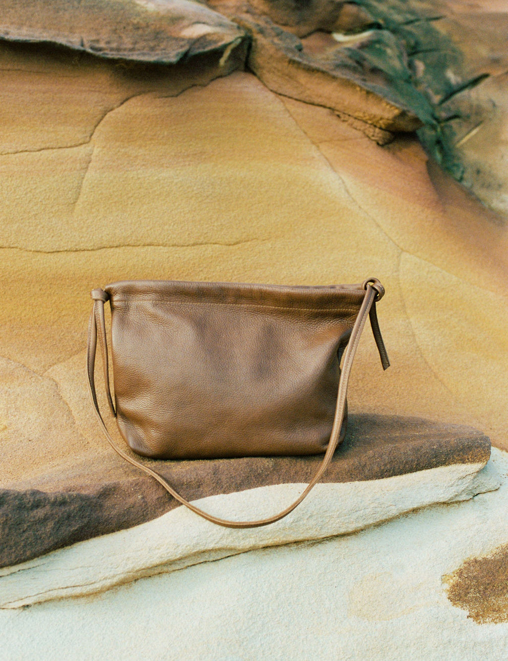 Brown leather handbag on a rock with natural background